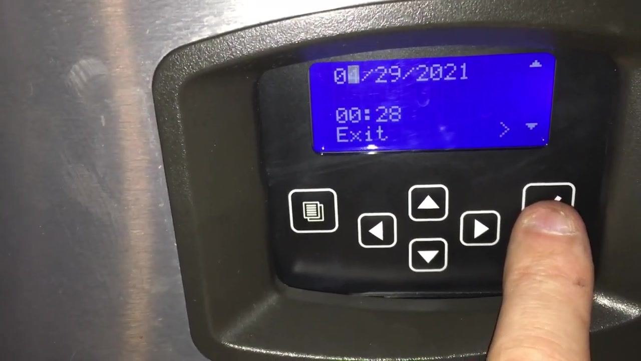 Control panel showing date, time, and navigation buttons, with finger pressing the right arrow