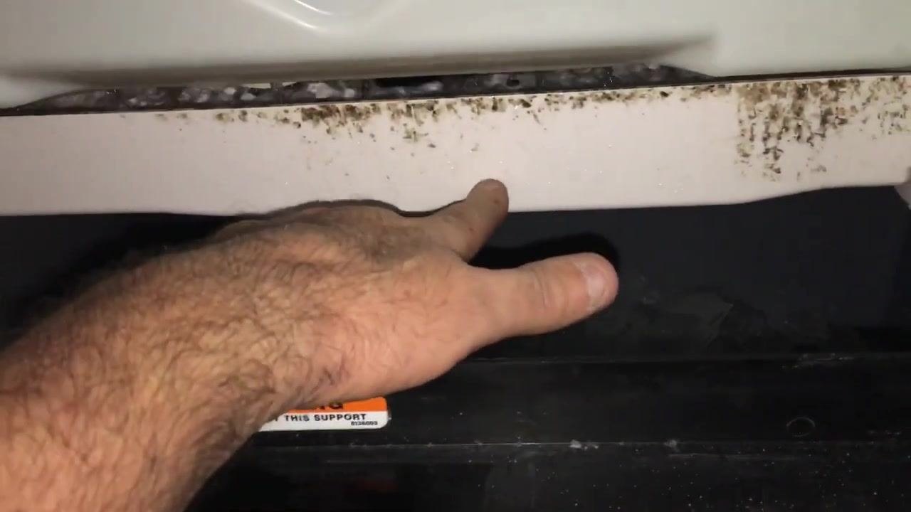 Hand reaching into the ice bin, with duct tape on the left, dirt on the white edge, and ice below