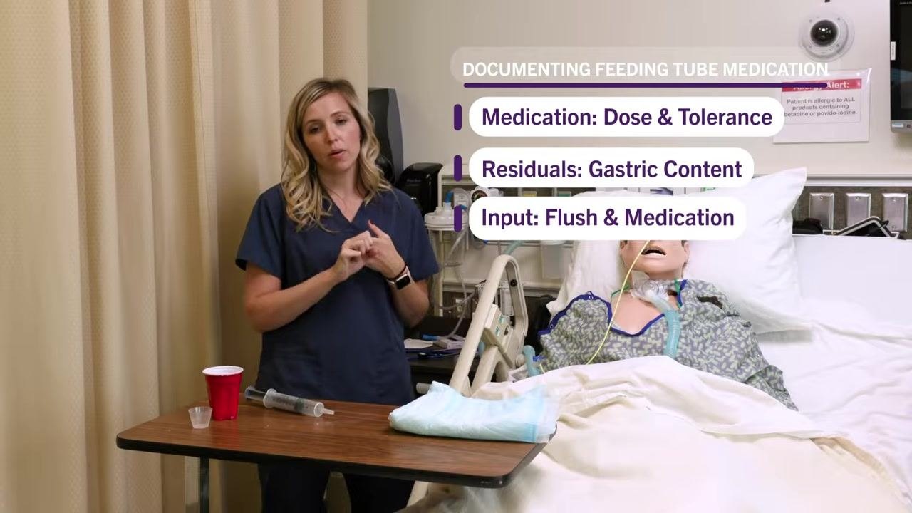 Nurse removing gloves at the bedside, syringe and supplies on the table, mannequin in bed.