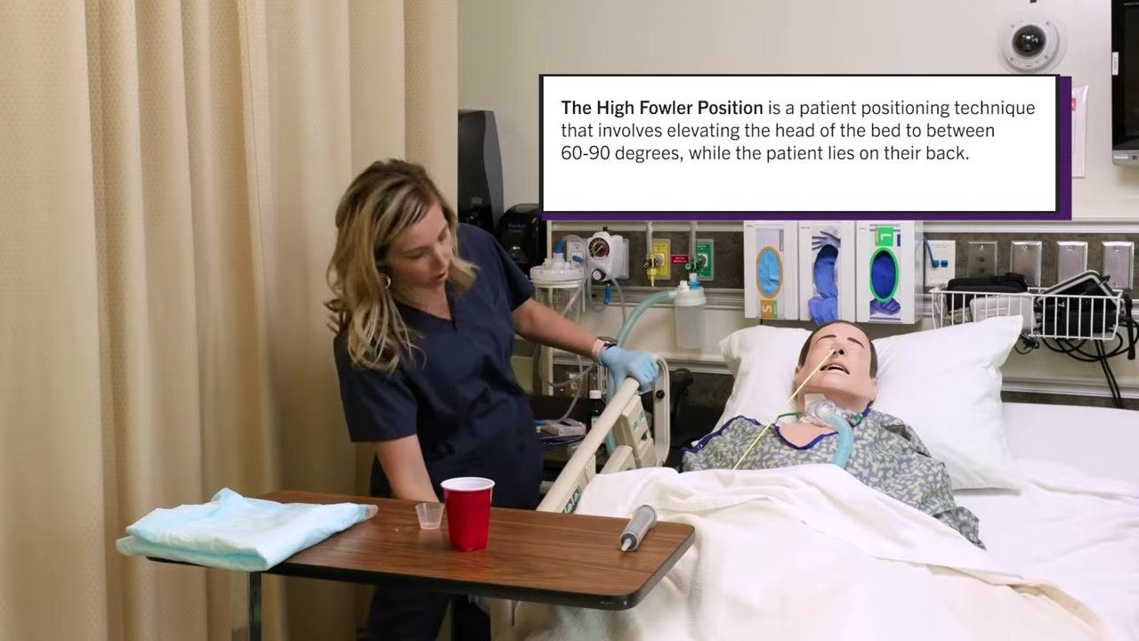 Nurse adjusting the bed to place the patient in High Fowler's position, with the definition displayed on screen. Patient mannequin with NG tube is in the bed.