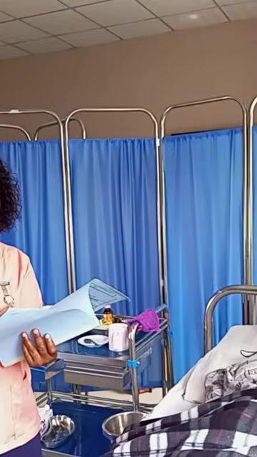 A nurse reviewing a patient folder at the bedside to confirm the prescribed medications and dosages, with a medication trolley visible nearby.