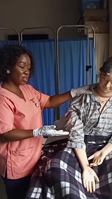 A healthcare worker placing a dark towel over the patient's chest to protect their clothing while they sit upright in bed.