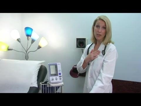 A doctor demonstrates both the hand-over-heart position and an arm-lowered position, illustrating correct and incorrect arm placement for blood pressure measurement.