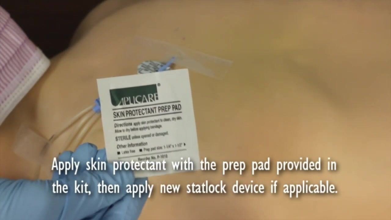 Gloved hand holding a skin protectant prep pad above the central line site.
