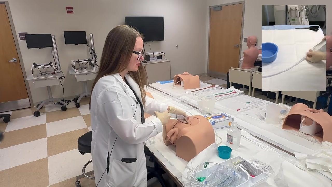 Irrigating the catheter on a training model, with an inset showing fluid return through the tubing