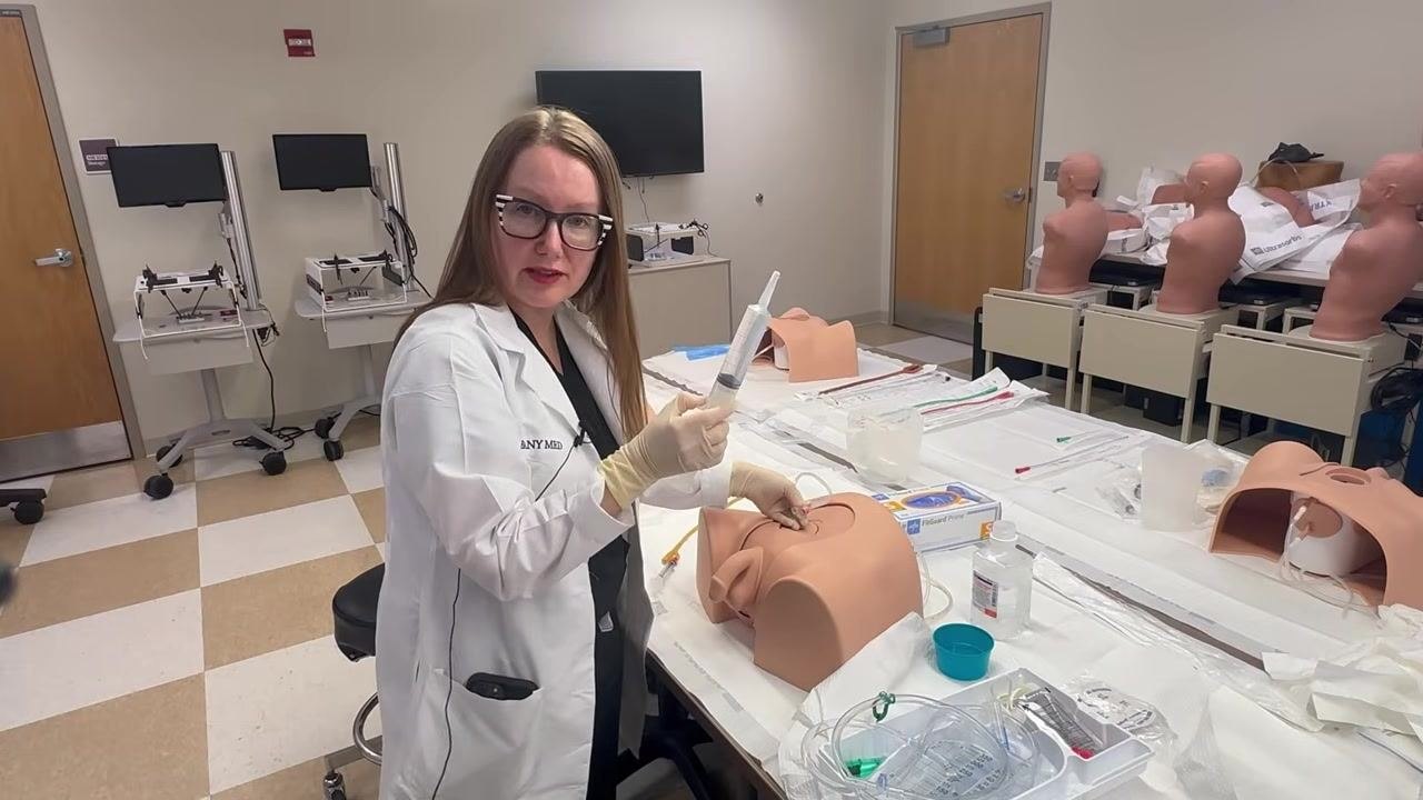Pointing to the catheter site to confirm balloon inflation and correct placement