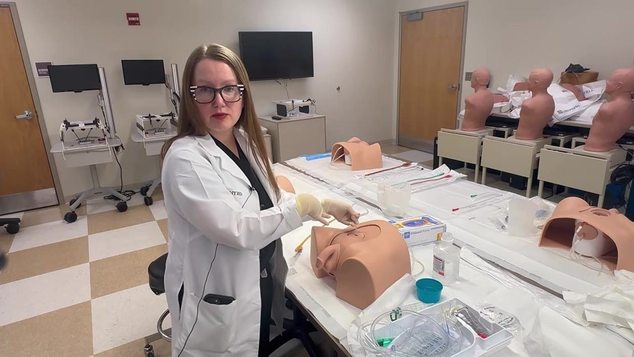 Connecting the drainage tubing to the catheter, with the setup visible on the training model