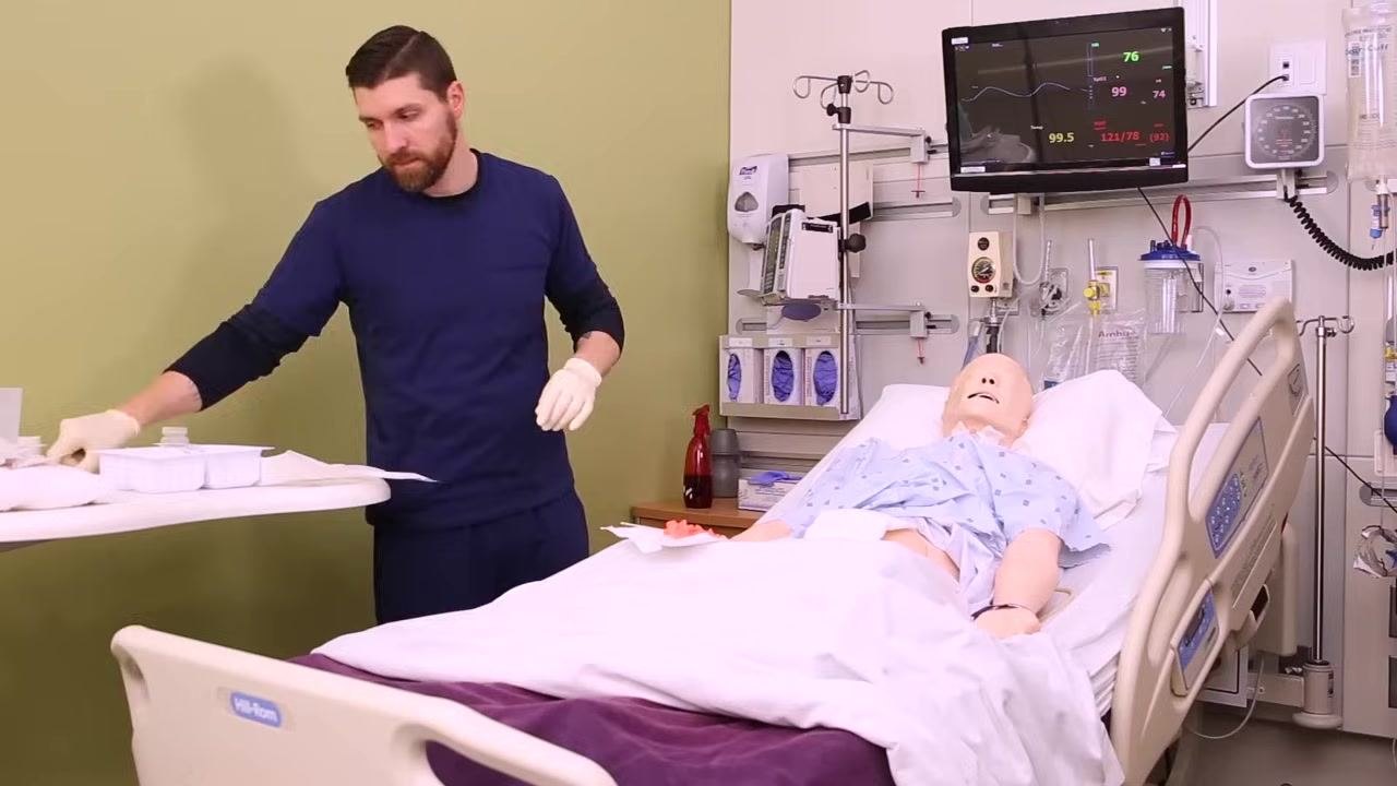 Nurse standing at the bedside with the wound now covered, no longer maintaining strict sterile technique