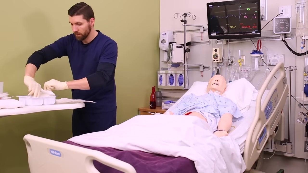 Nurse separating gauze into portions, with some pieces being soaked in sterile saline, supplies arranged on a clean table, patient mannequin in bed
