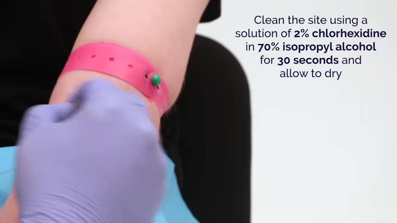 Gloved hand cleaning the patient's arm above a pink tourniquet