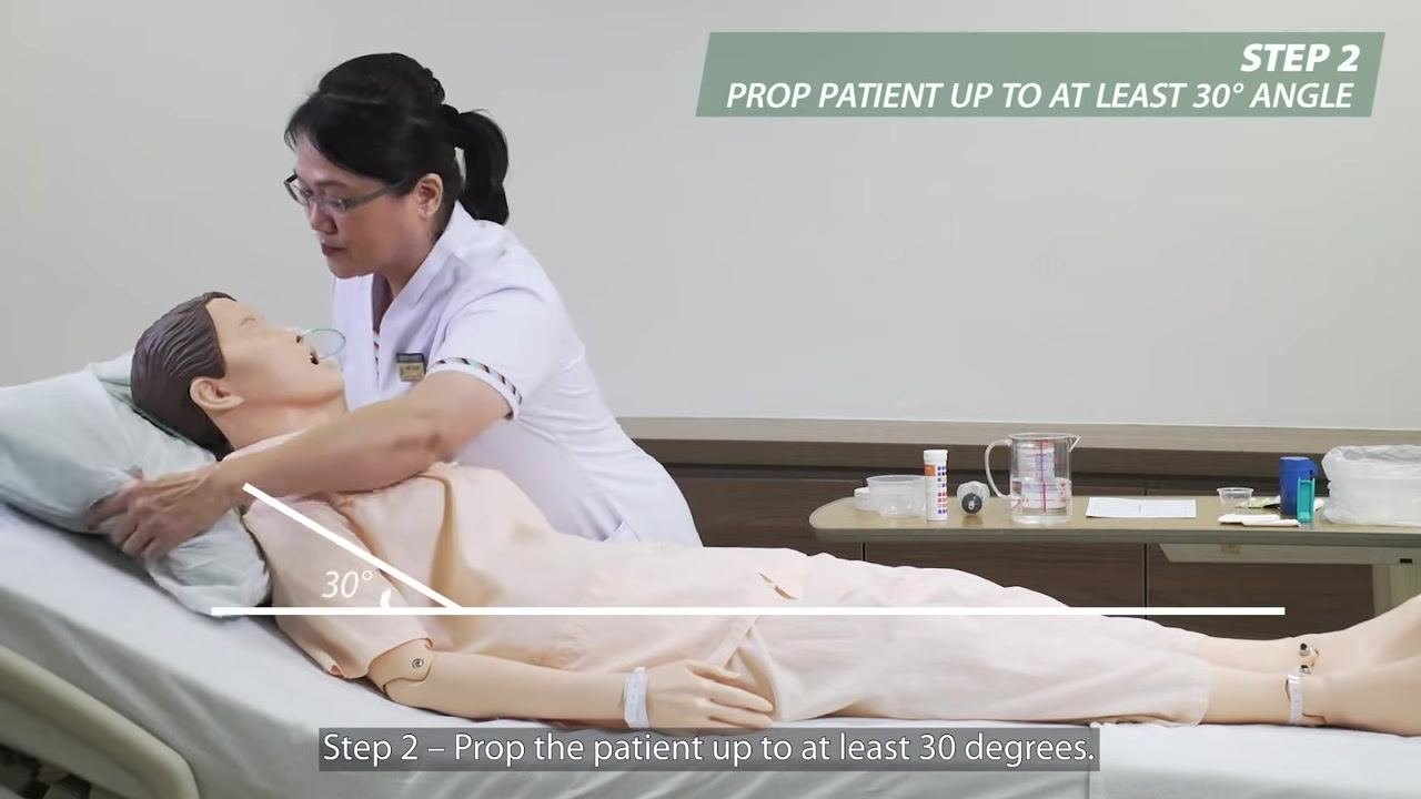 A nurse measuring the external length of the feeding tube at the patient's nostril