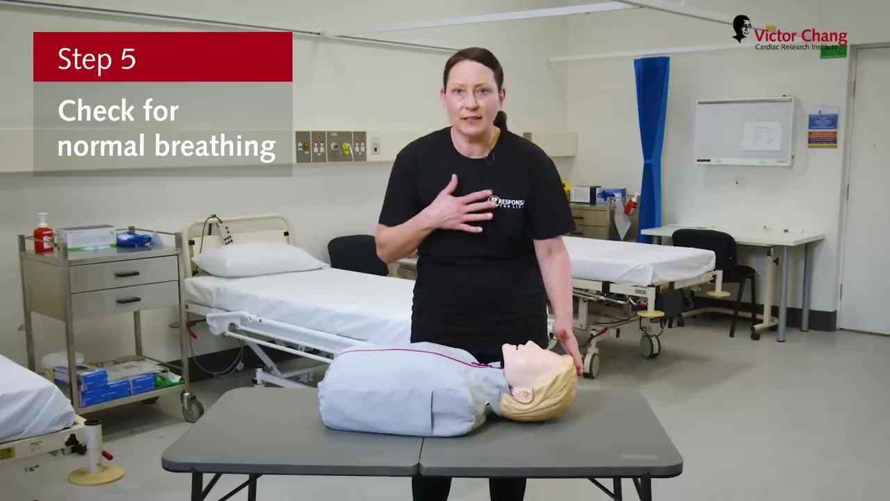 Demonstration gesturing toward the chest, with on-screen text "Step 5: Check for normal breathing."