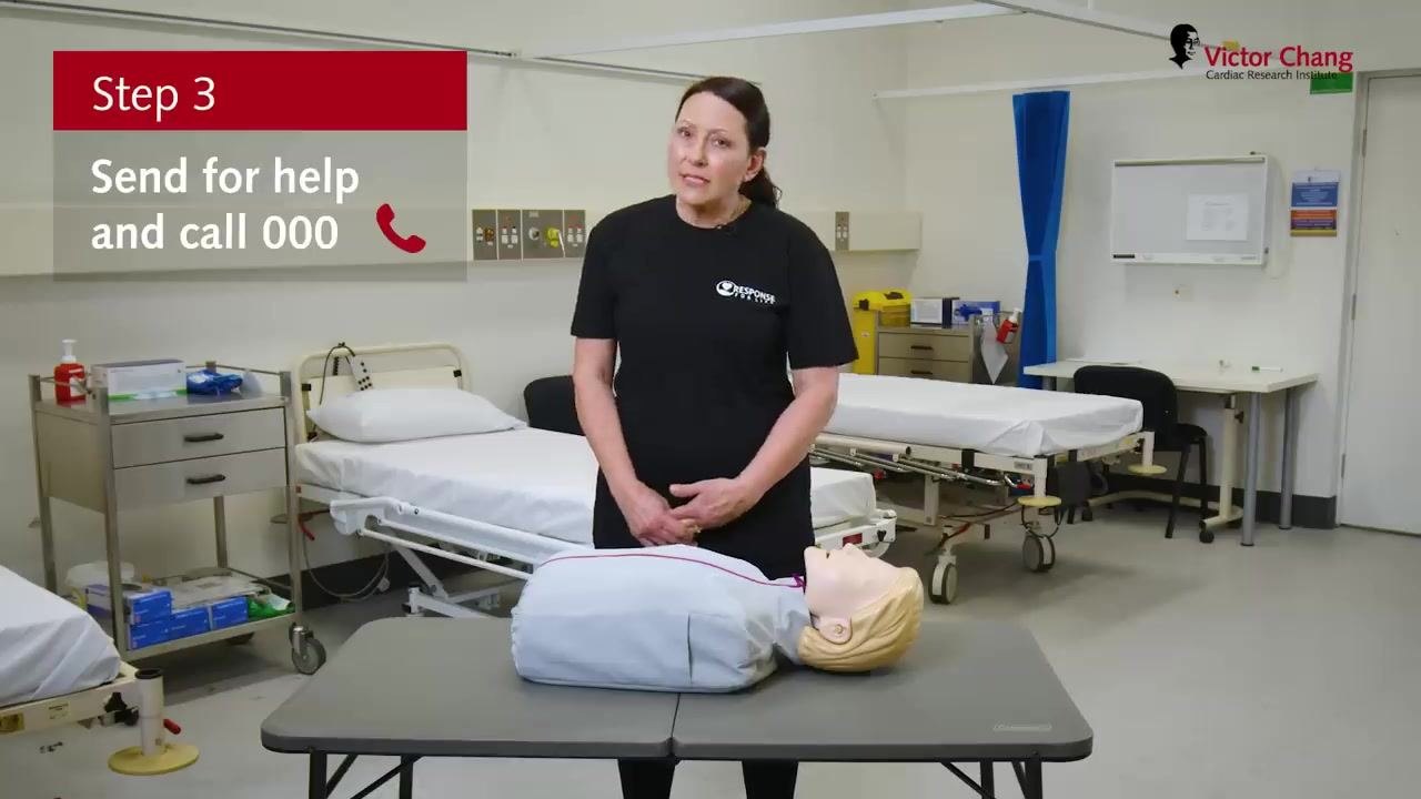 Instructor standing next to a manikin with hands together, on-screen text "Step 3: Send for help and call 000" and a phone icon.