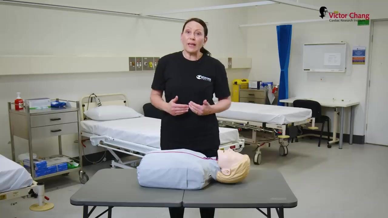 Preparing to give a rescue breath to a manikin after tilting the head back.