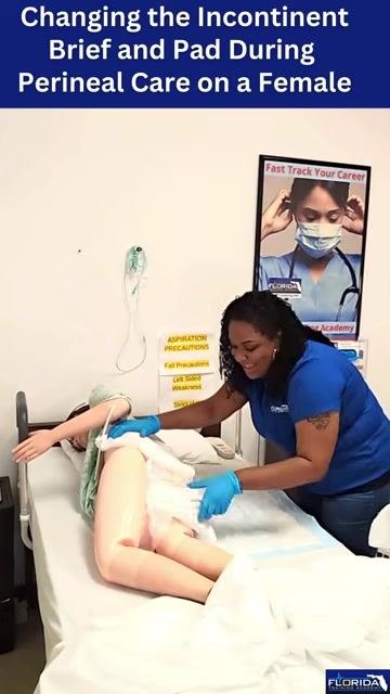The caregiver secures the diaper fasteners on the mannequin, working from one side of the bed.