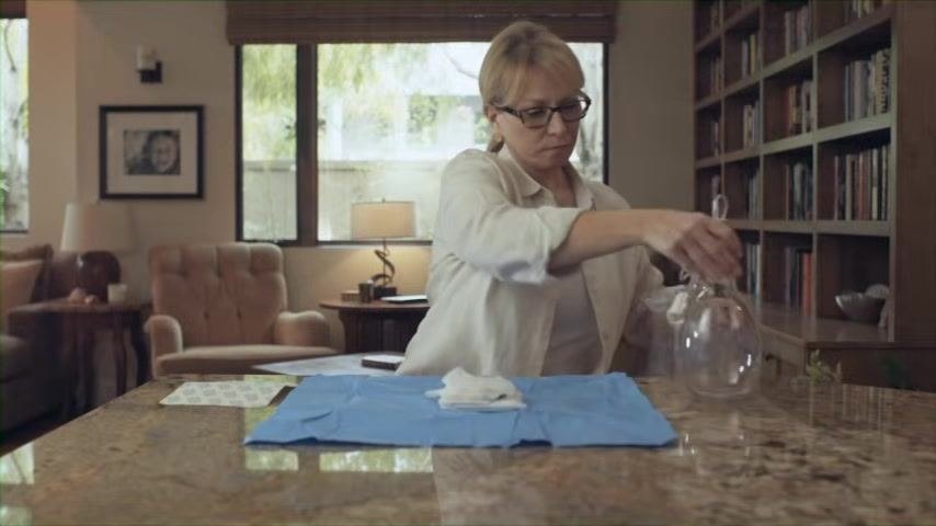 Close-up of hands unfolding the blue sterile wrapping on a countertop to create a sterile field.