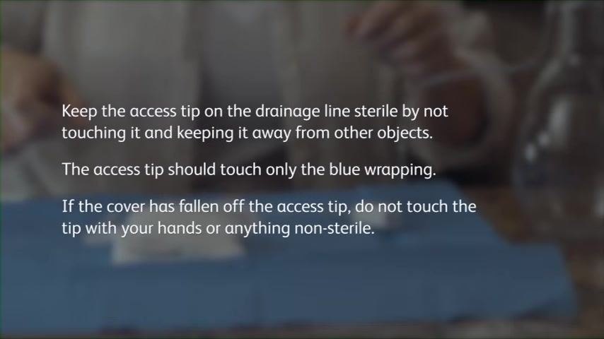 A person in a home setting with a blue sterile wrap on a countertop. Text overlay: "Keep the access tip on the drainage line sterile by not touching it and keeping it away from other objects. The access tip should touch only the blue wrapping. If the cover has fallen off the access tip, do not touch the tip with your hands or anything non-sterile."