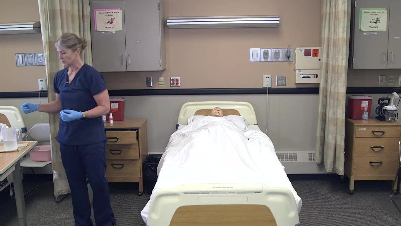 Nursing assistant in gloves preparing to dispose of urine and clean the graduated cylinder in the resident's bathroom