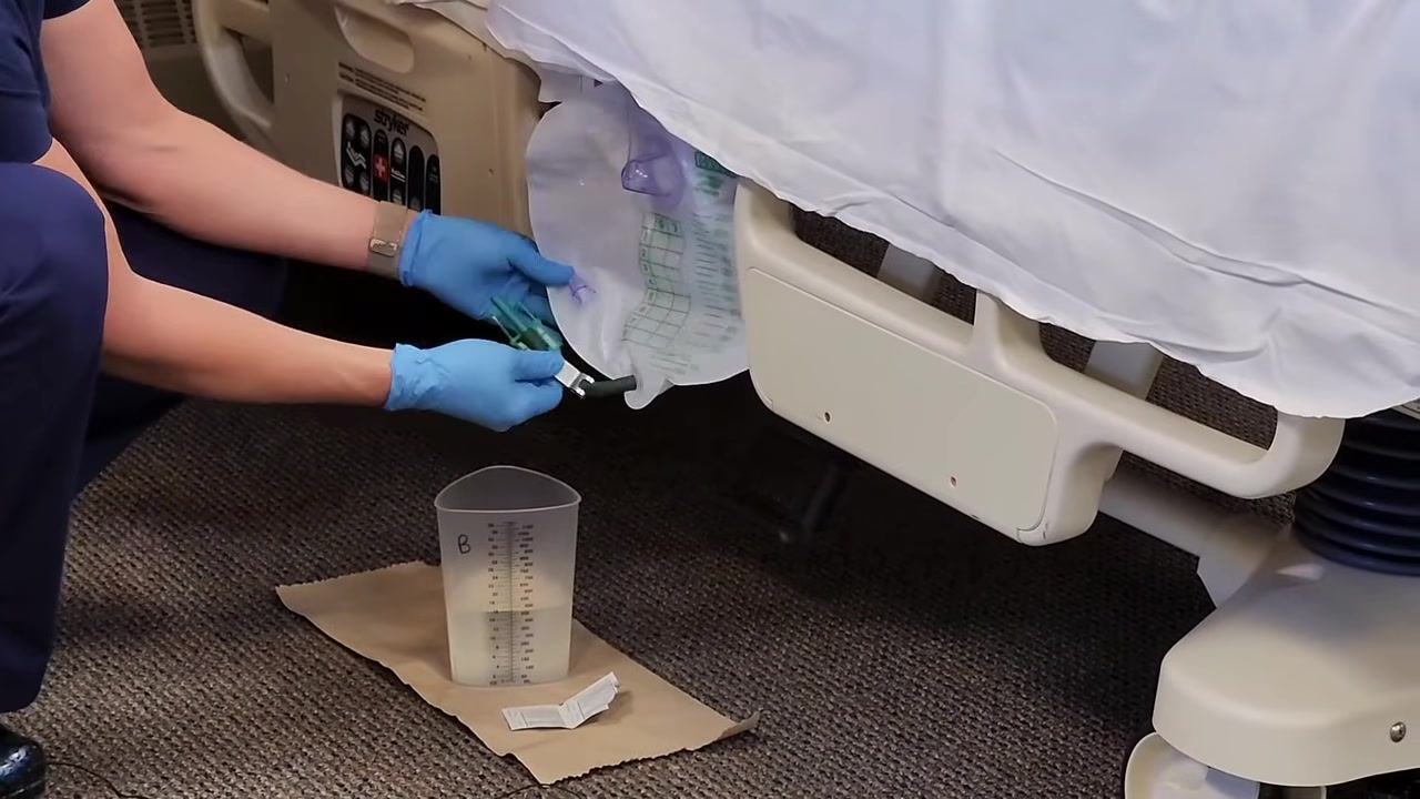 Graduated cylinder with urine placed on a barrier on the overbed table, with hand sanitizer nearby