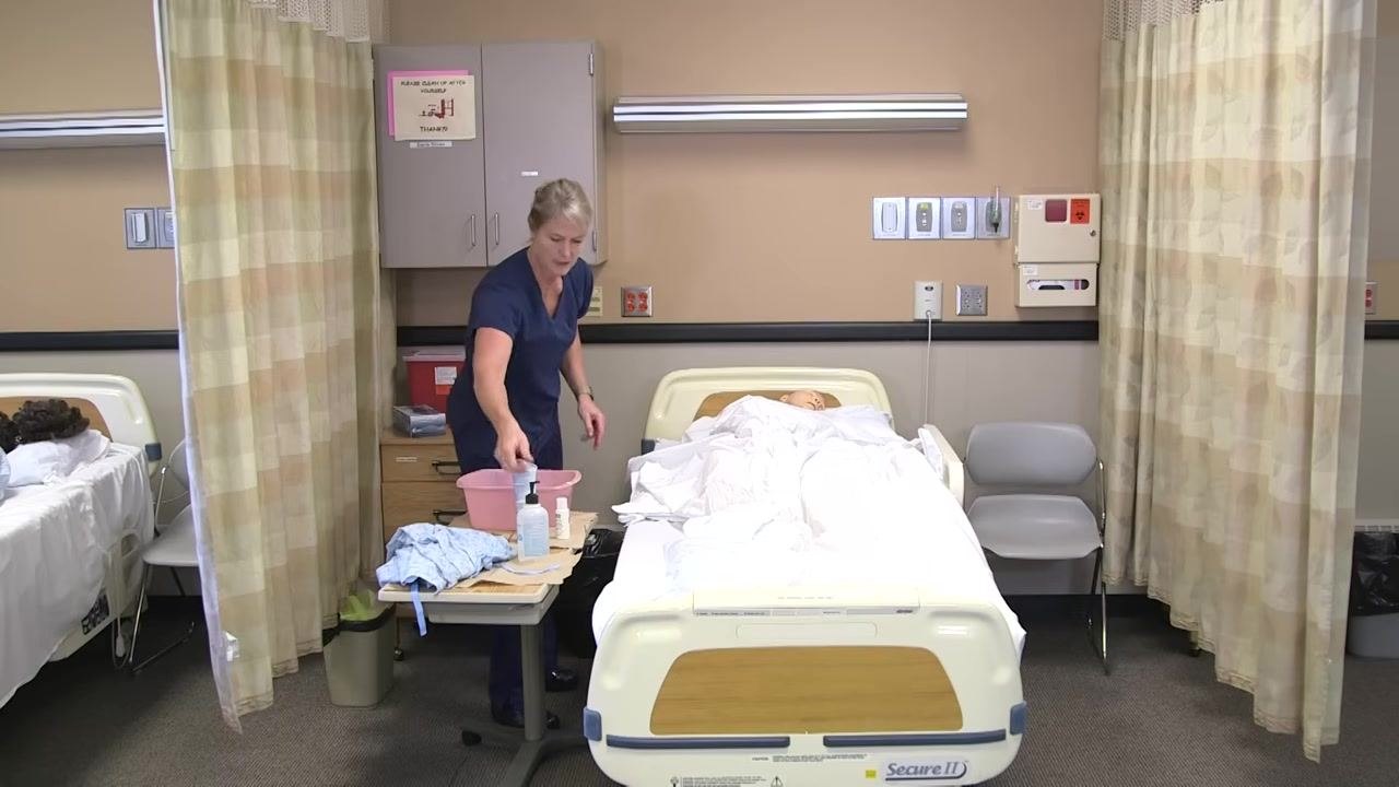The healthcare worker is drying the patient's back with a clean towel, ensuring the area is completely dry.