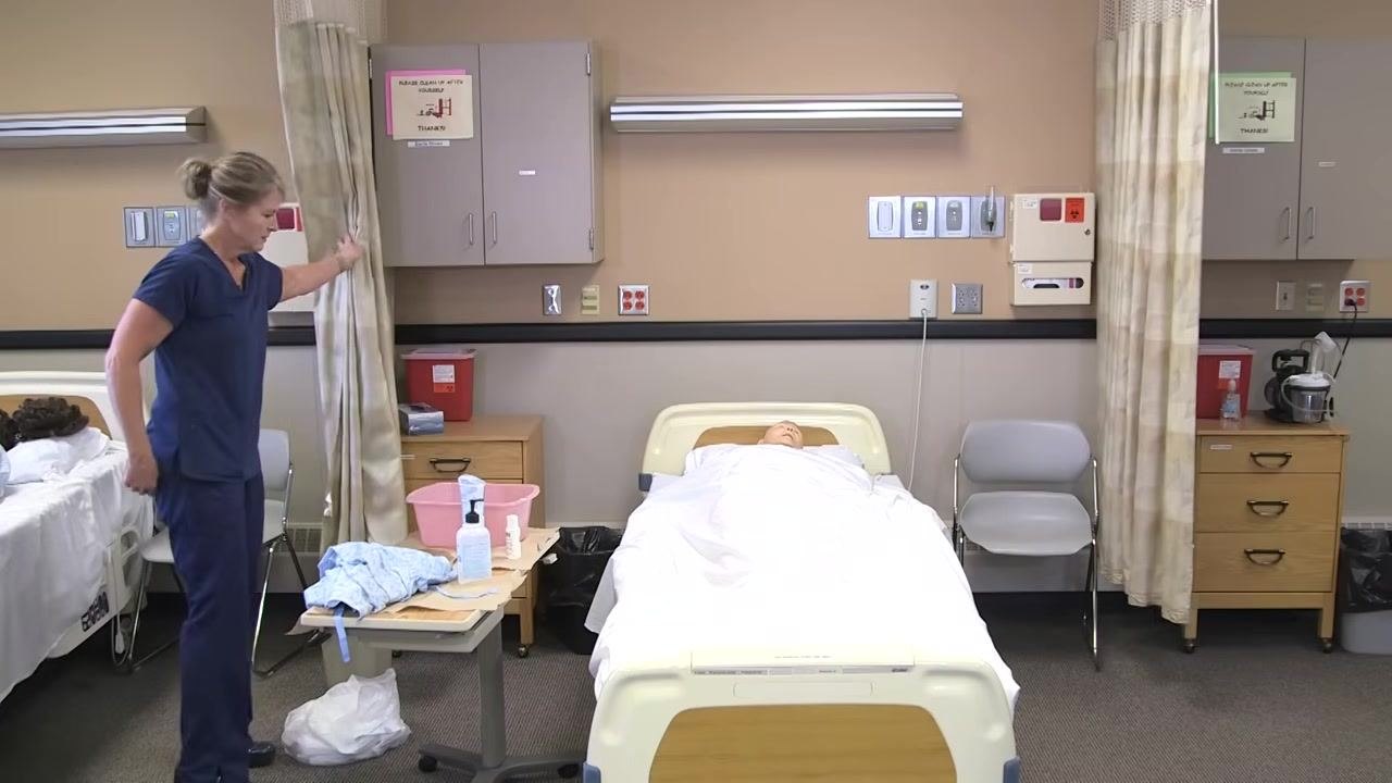 The healthcare worker is at the side of the bed, lowering the side rail and ensuring the call light is accessible.