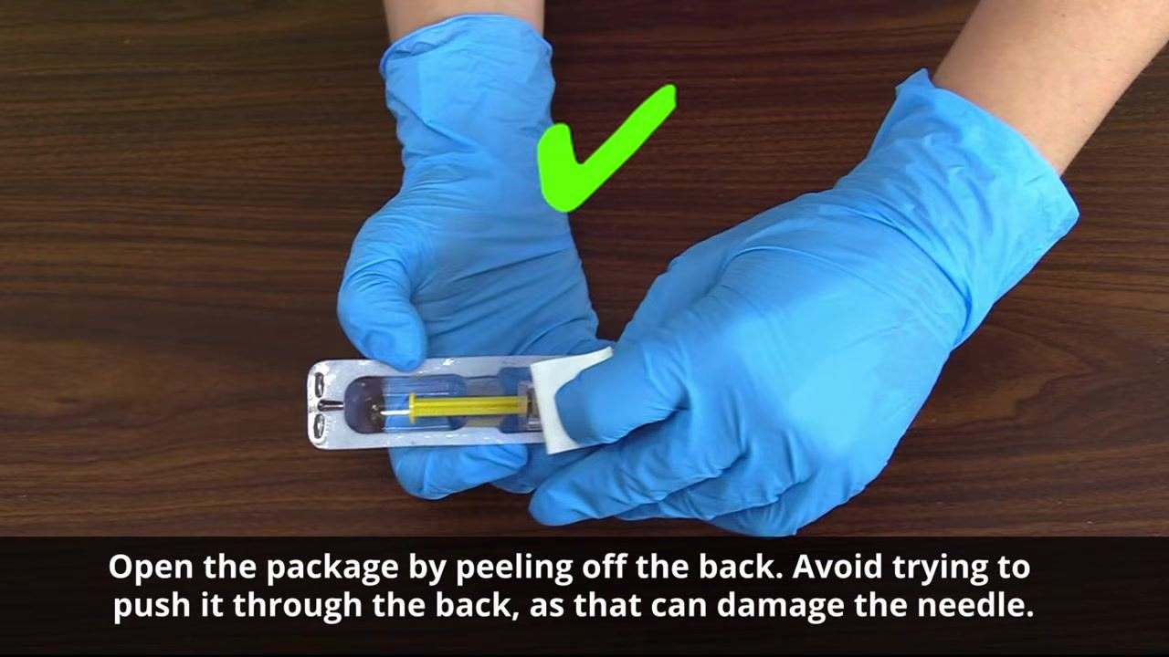 Gloved hands peeling back the label of a pre-filled syringe package, shown with a green check mark for correct technique.