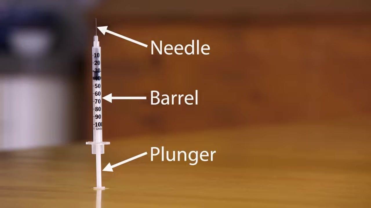 Close-up of a syringe standing upright with its measurement markings clearly visible.
