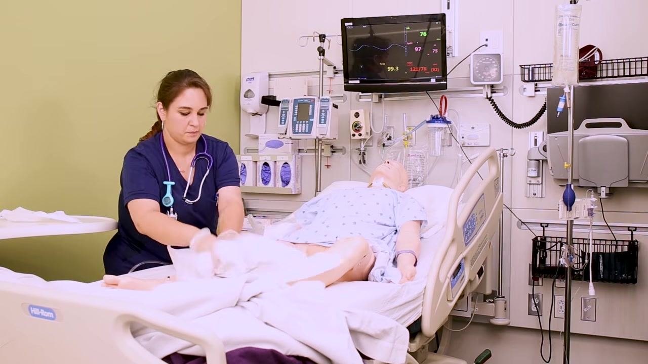 A nurse removes the drape and begins cleaning up supplies after securing the Foley catheter and drainage bag, ensuring the patient is covered and comfortable.