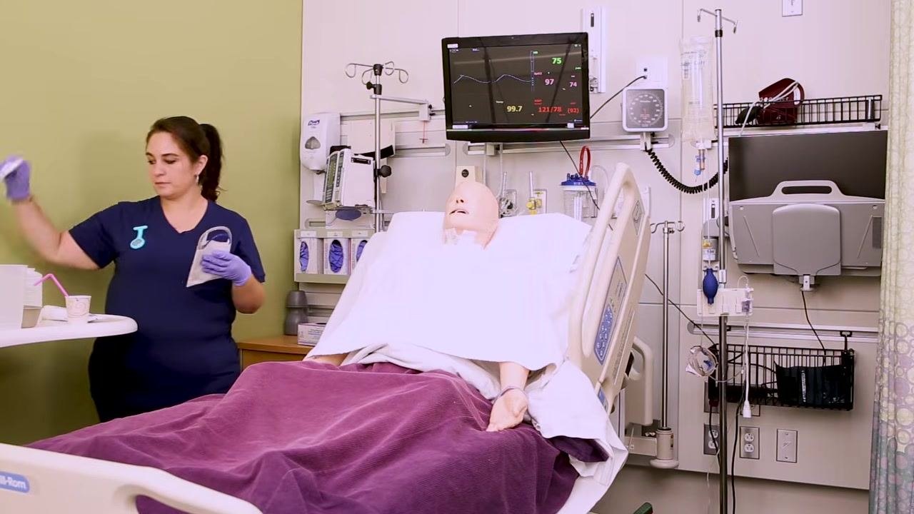 Nurse holding the NG tube and preparing to measure the length needed for insertion, standing next to a patient mannequin