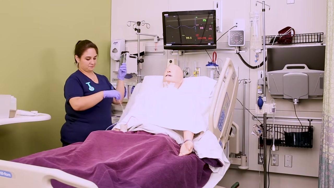 Nurse standing next to a patient mannequin, preparing for the next step in the NG tube insertion process