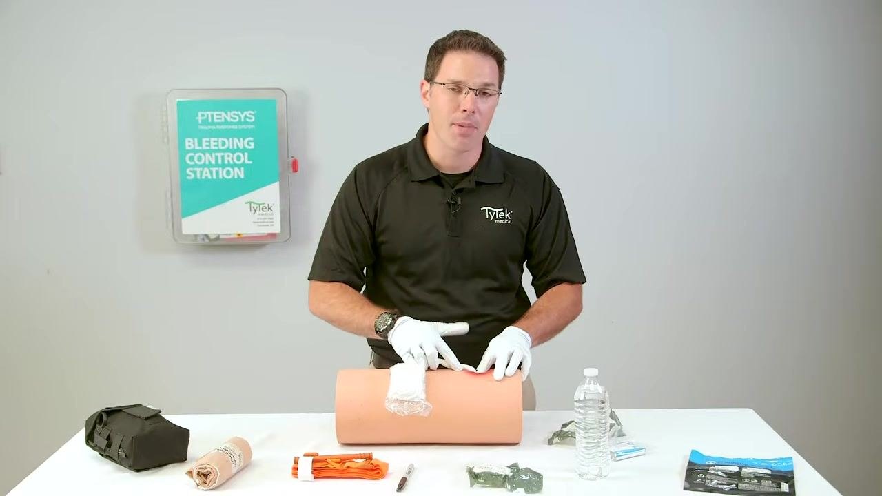 Pointing to the wound trainer while emphasizing safety precautions.