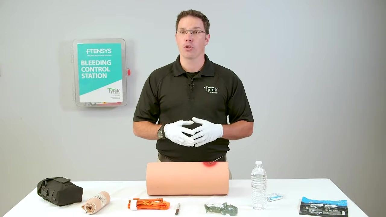 Explaining the wound packing procedure with supplies and trainer on the table.