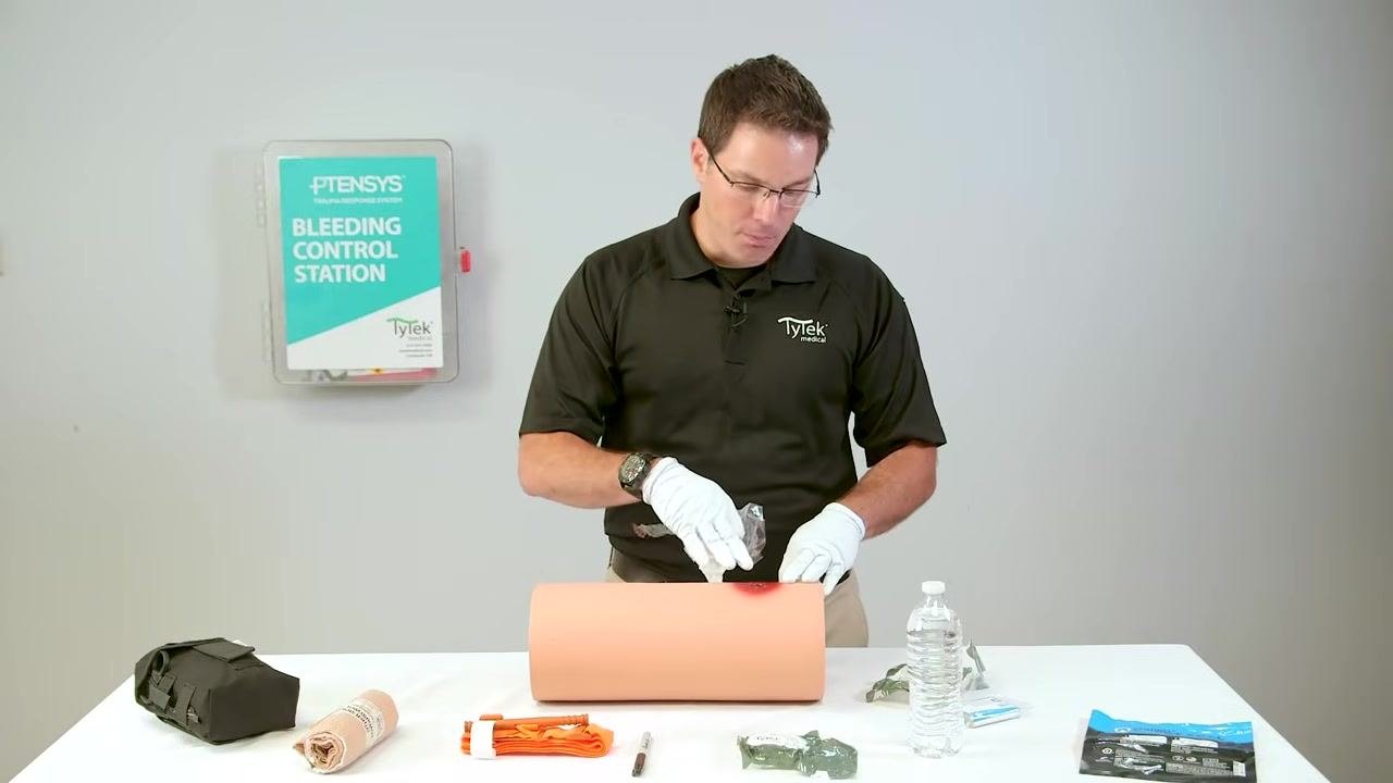 Applying gauze directly to the active bleeding point on the wound trainer.