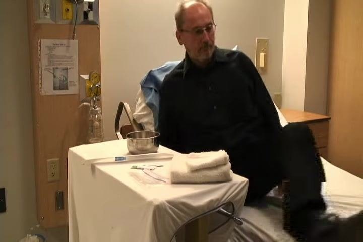 Sitting on the edge of a bed with supplies arranged on a bedside table, preparing for the procedure