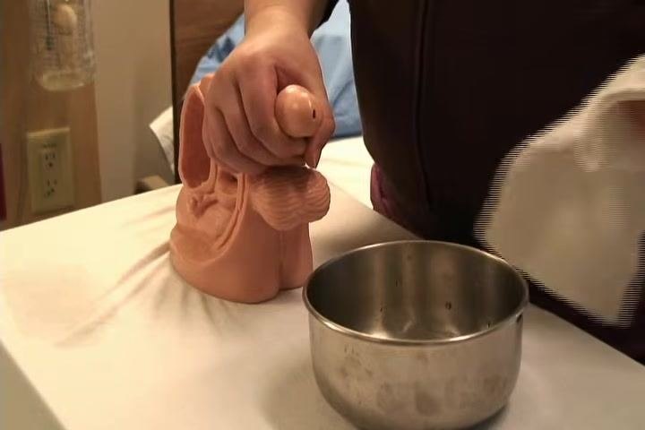 Retracting the foreskin and preparing to clean, with a metal bowl and washcloth visible