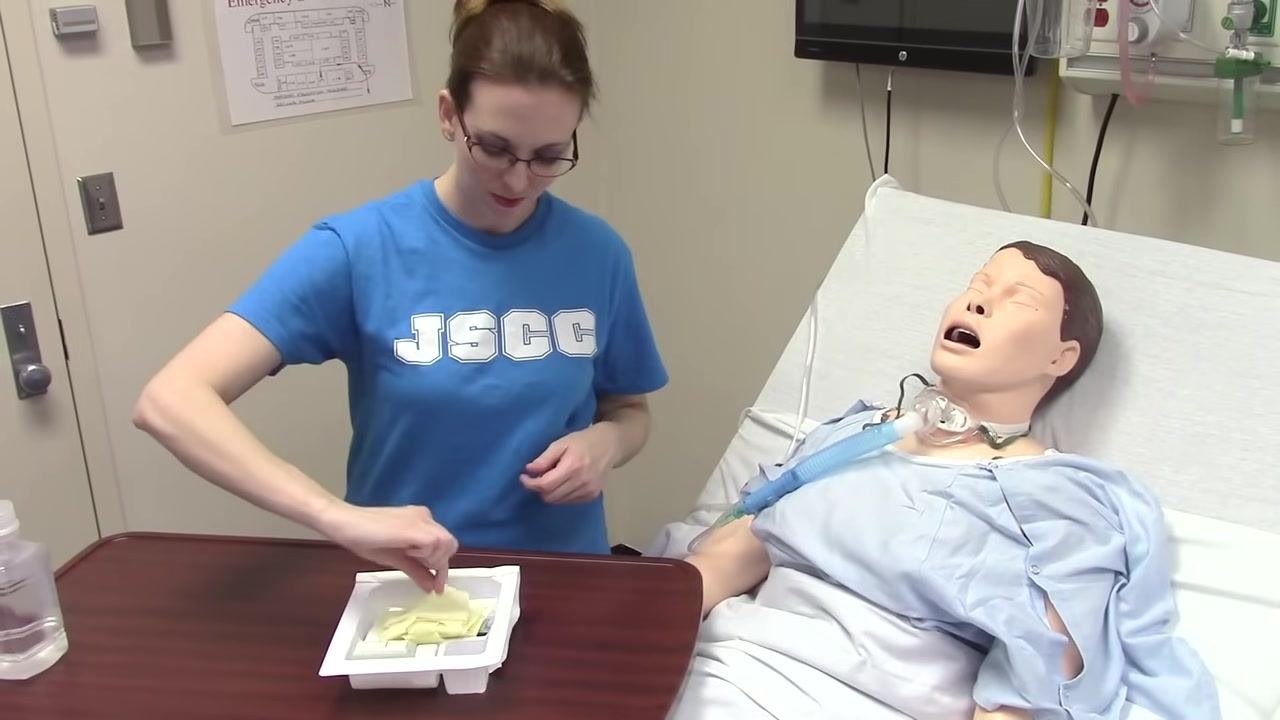 The tray is placed on the table while the sterile glove package is opened, preparing to don gloves.