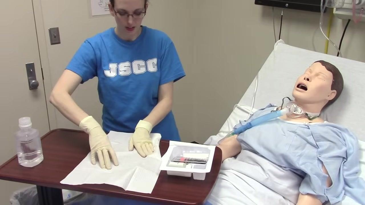 Sterile-gloved hands and supplies remain within the sterile field on the table.