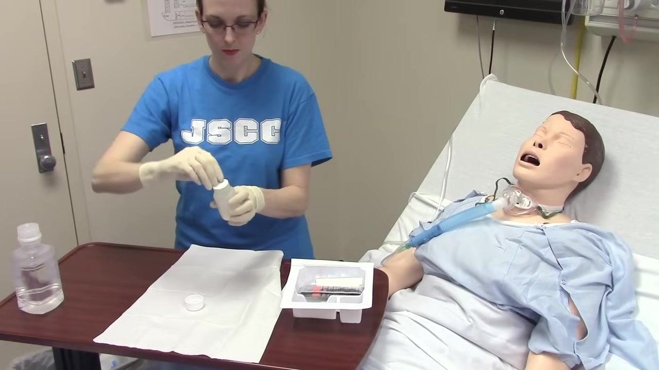 A small bottle is opened, preparing to empty its contents onto the sterile field.