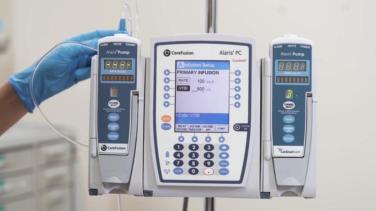 The Alaris PC screen shows RATE = 100 mL/h and VTBI = 900 mL being entered via the keypad.