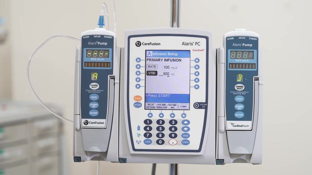 The Alaris PC screen displays the "Press START" prompt with RATE = 100 mL/h and VTBI = 900 mL set, and Channel A active.