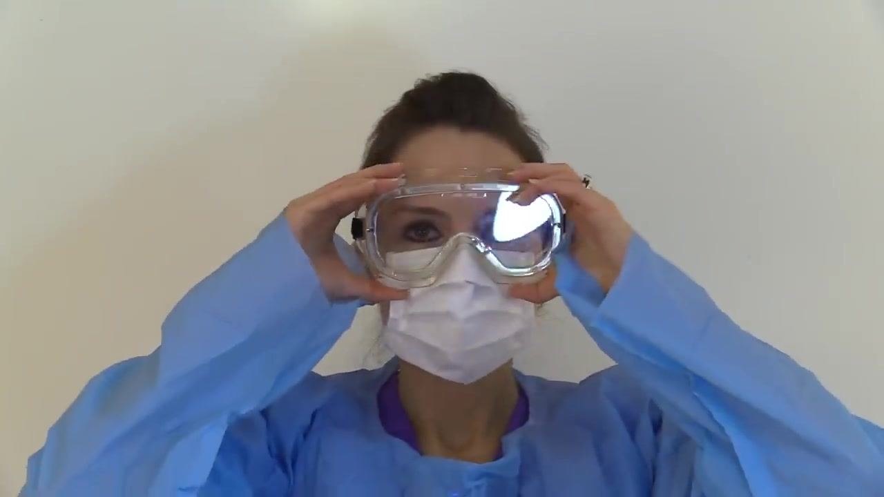 A staff member wearing a respirator places both hands over the mask to perform a seal check.