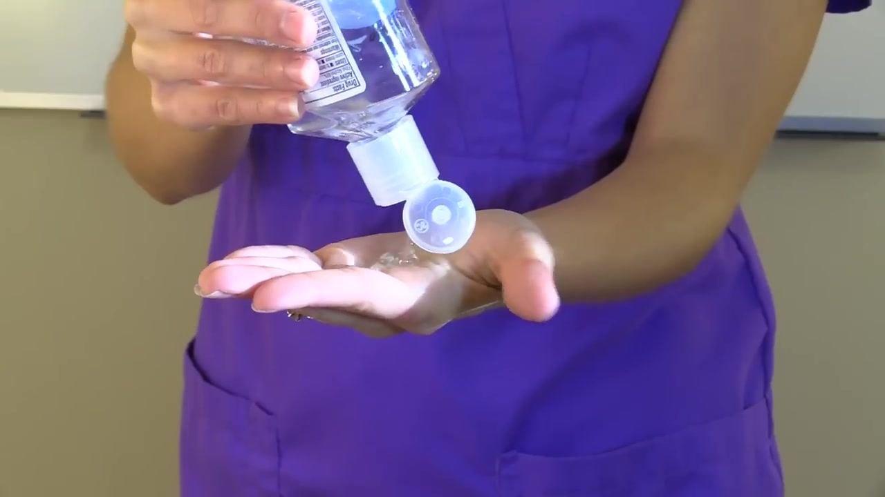 A staff member ties the isolation gown securely at the back.