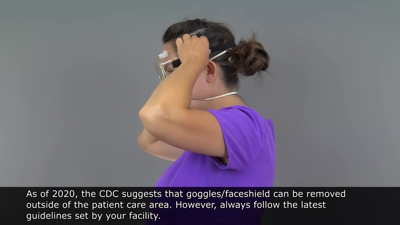 Person in purple scrubs, wearing a surgical mask. Large red X and text: "Avoid touching the front of mask after exposure."