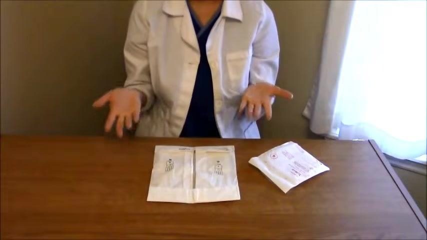 A nurse in a white coat sits at a table with two sterile glove packages and an additional medical package, hands positioned above the table in preparation to open them.