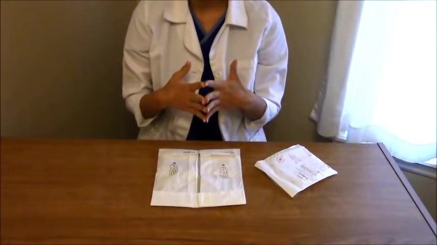 Close-up of hands positioned above an open sterile glove package, reaching underneath the creased edges without touching the gloves.