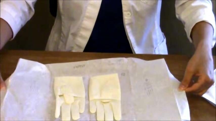The inner wrapper of the sterile glove package is pulled open and flattened, fully exposing both gloves within the two-inch safe border.