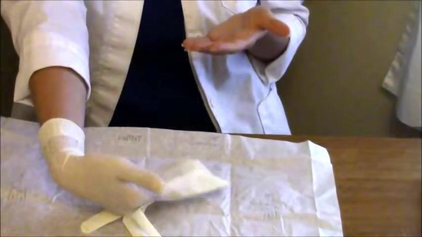 The non-dominant hand is guided into the second glove by the gloved dominant hand, with the thumb tucked in as the glove is pulled fully on.