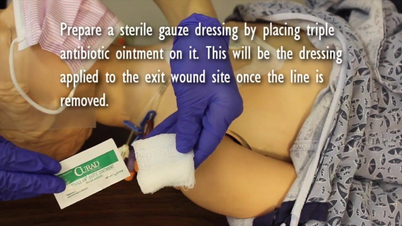 Nurse holding a packet of triple antibiotic ointment and a piece of sterile gauze, preparing the post-removal dressing.