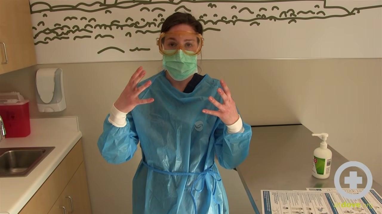 Person in PPE continuing to remove the second glove, showing one bare hand and one gloved hand.