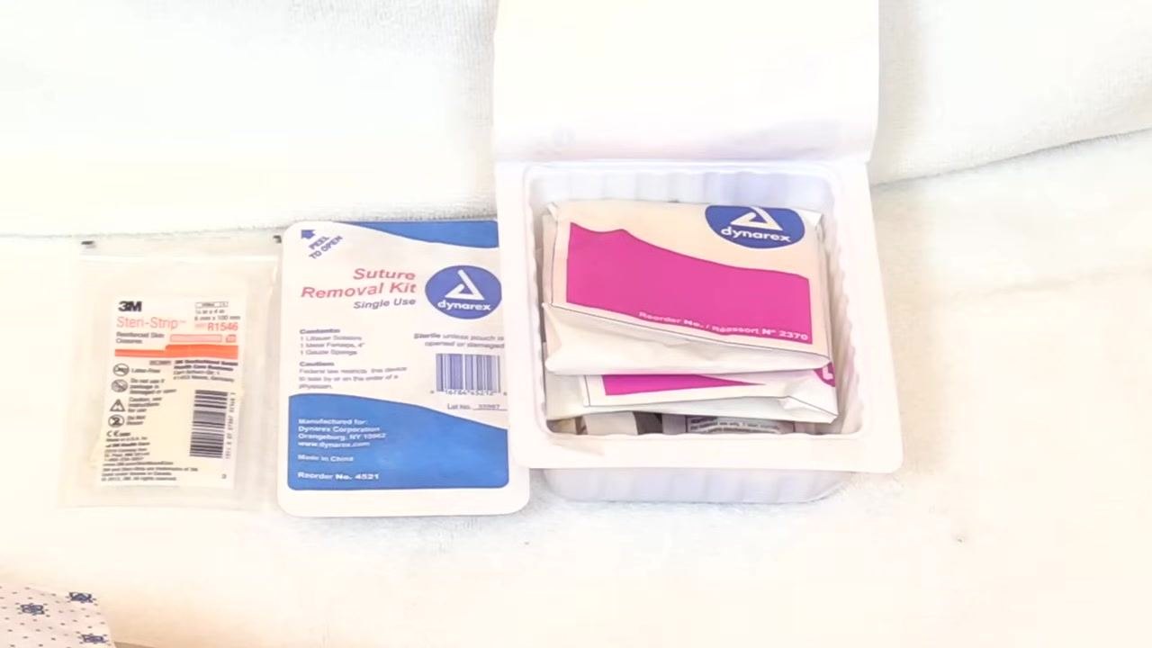 Dressing change tray opened, with wrapped sterile items, the suture removal kit, and Steri-Strips arranged on a white towel.